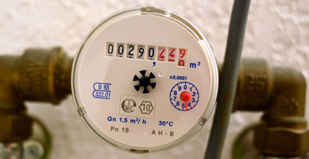 Un compteur de gaz dans un local technique de copropriété avec des tuyaux et des étiquettes d'identification